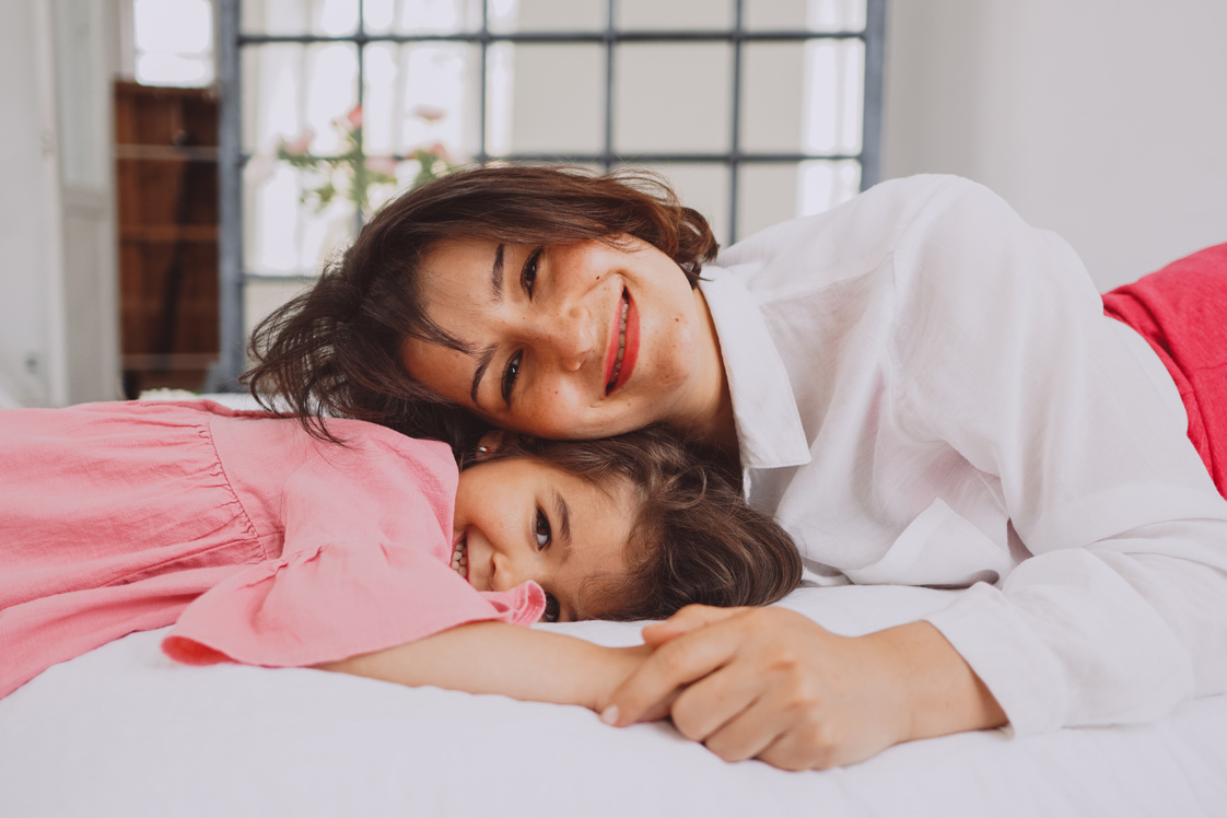 Smiling Mother Resting on Little Daughter's Head While Holding Hands